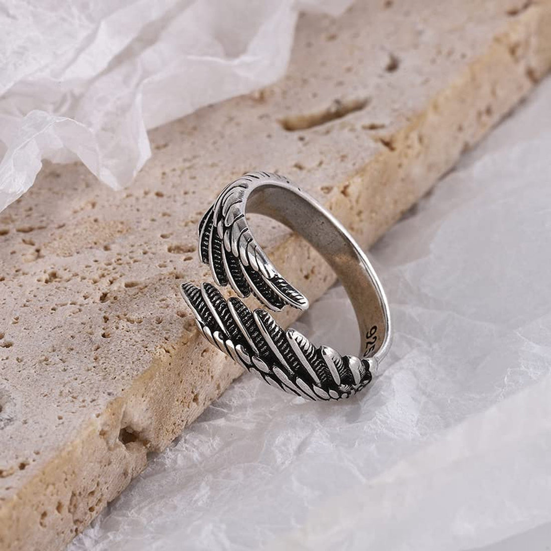 Sterling silver feather ring on pale stone and soft white fabric