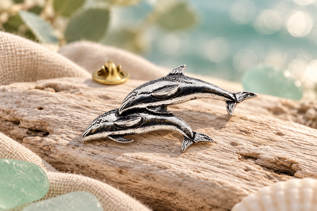 Double-dolphin pewter lapel pin in a coastal setting
