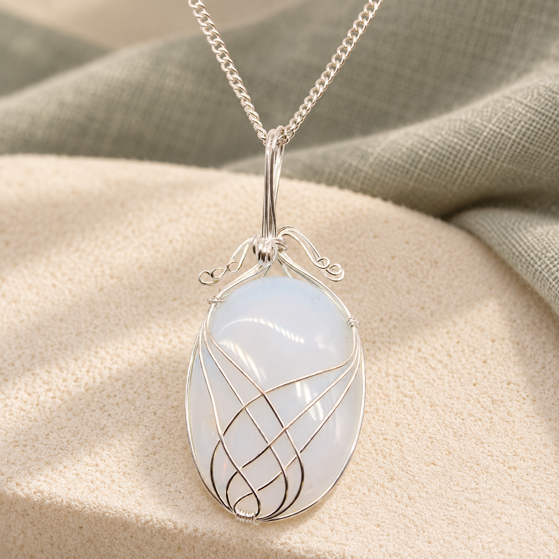 Opalite swirl pendant necklace on cream fabric with muted sage linen