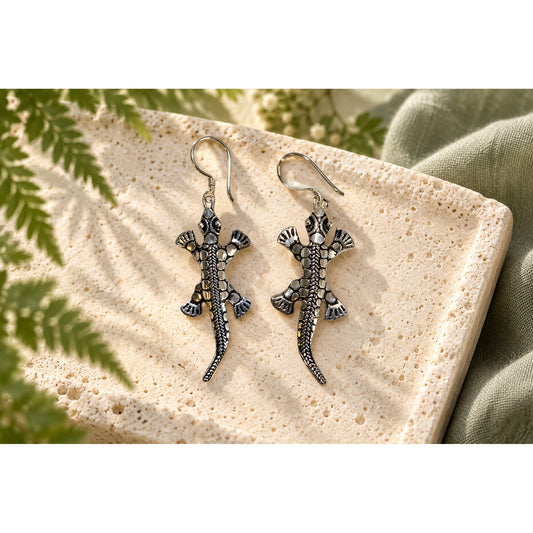 Silver lizard earrings on limestone with a botanical backdrop