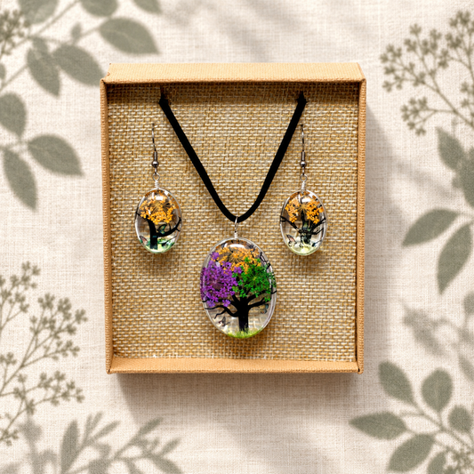 Pressed flower tree-of-life necklace and earrings in a woven box on cream linen with botanical shadows